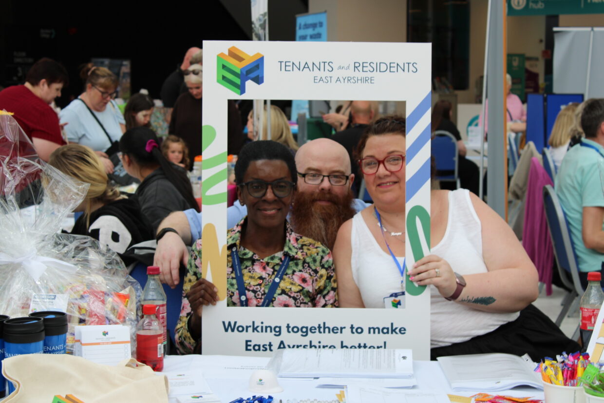 East Ayrshire FED members smiling at their stall while holding a selfie board