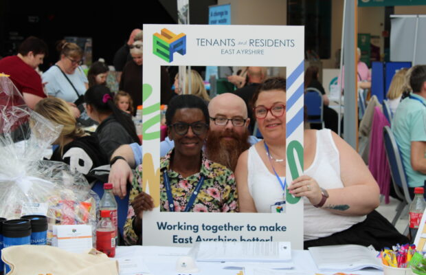 East Ayrshire FED members smiling at their stall while holding a selfie board